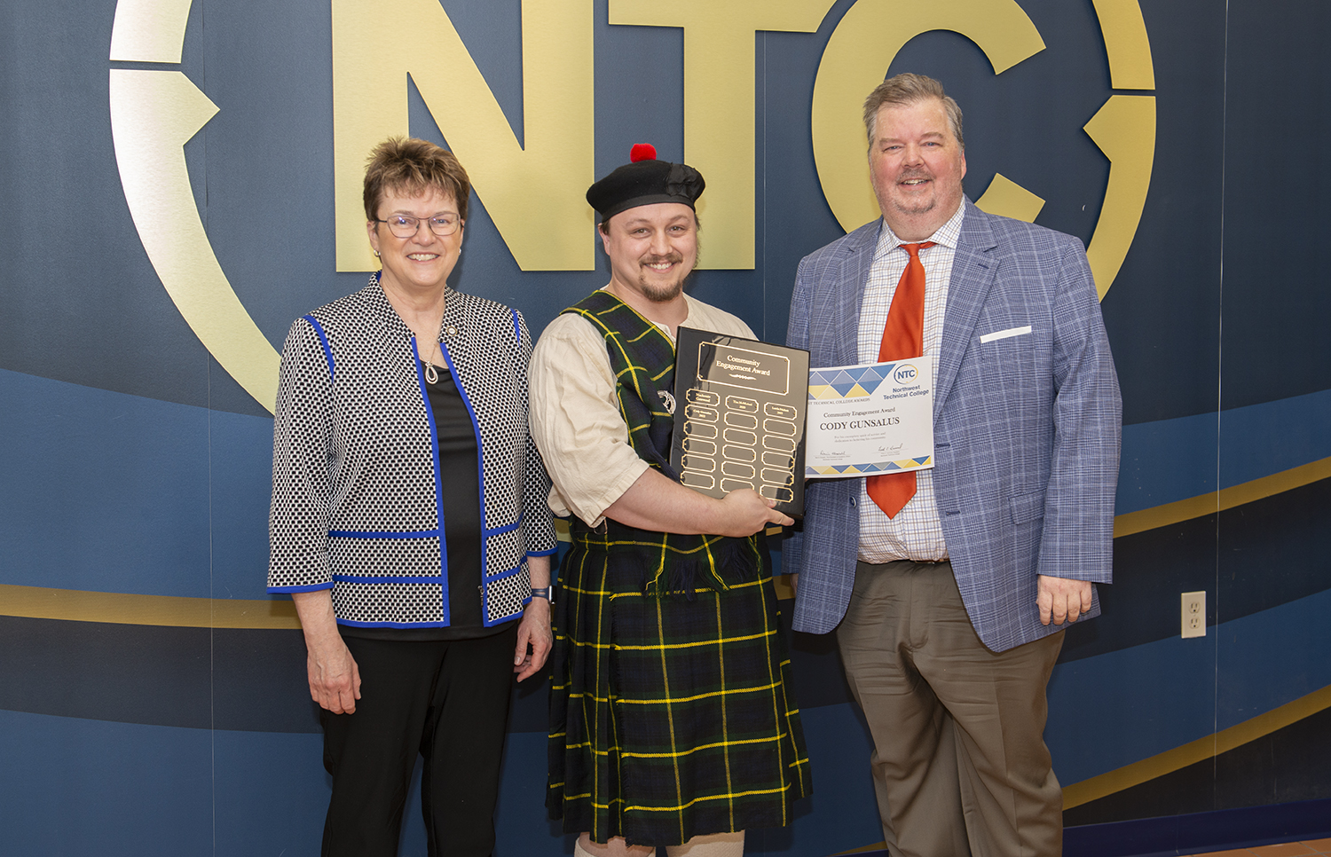 Cody Gunsalus holding his community engagement student award and plaque.