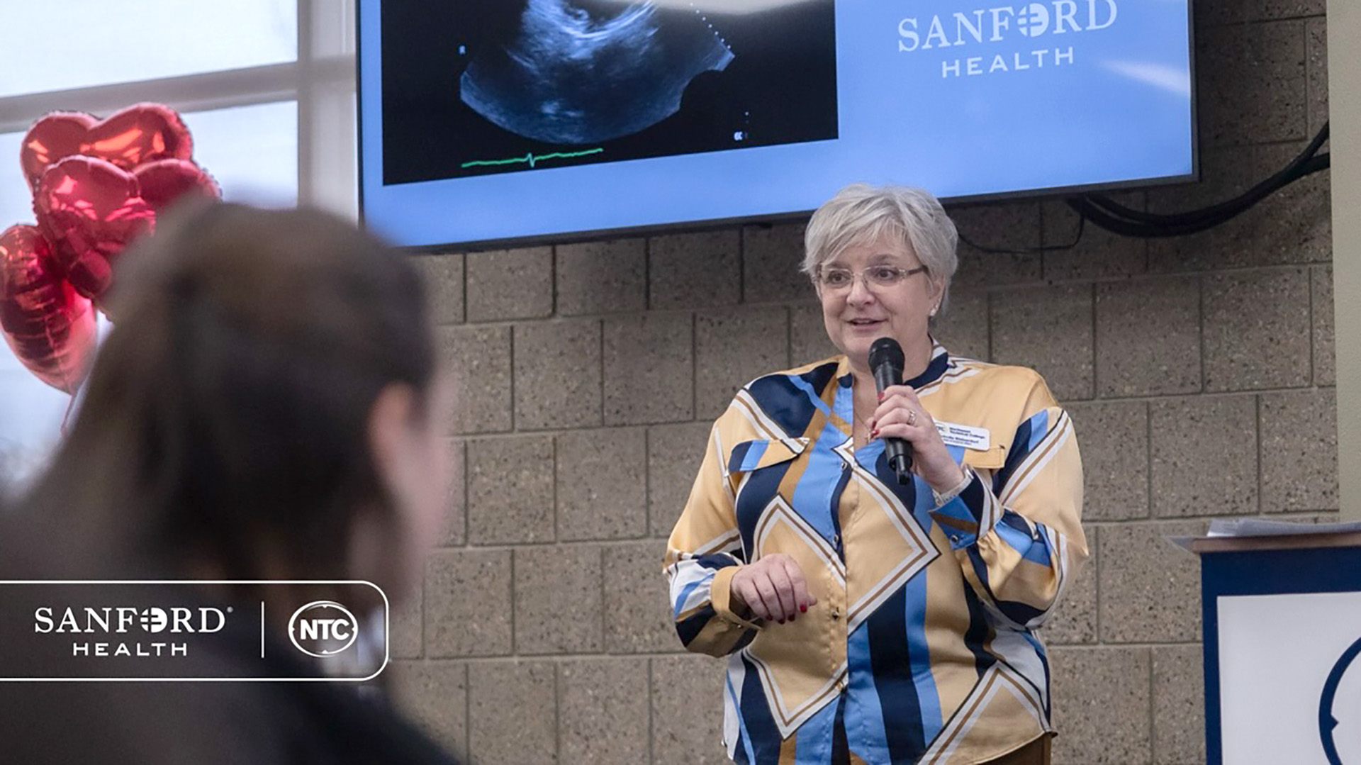 Nicholle Bieberdorf stands in front of a screen showing a heart sonogram during NTC's Cardiac Sonography information night.