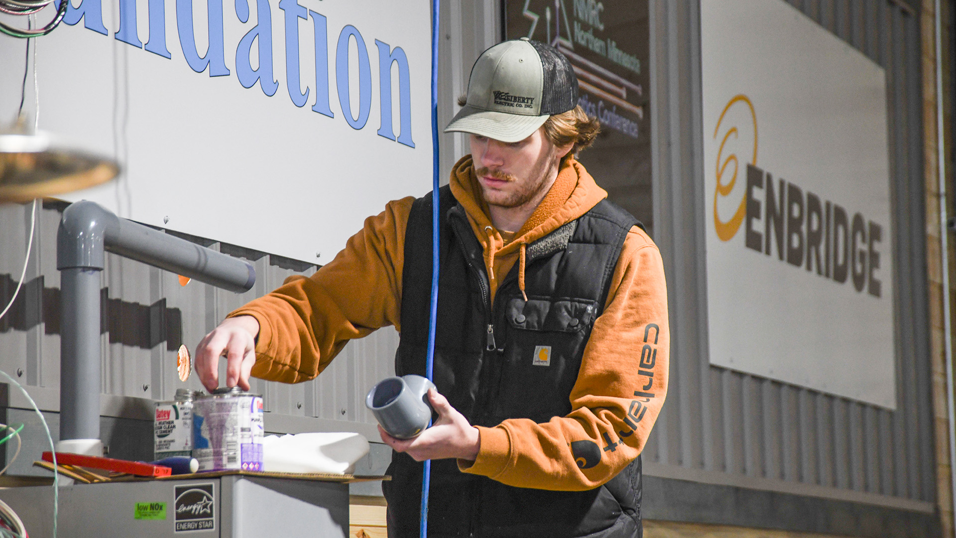 An NTC student applies glue to a PVC pipe that will be attached to a boiler at the North STAR Robotics facility.