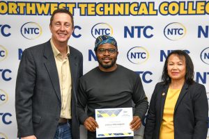NTC student Joshua Olorunyemi holds a certificate. NTC President John Hoffman is on the left, and Vice President Ketmani Kouanchao is on the right.