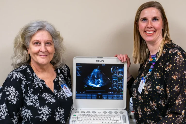 Two people posing next to a medical device.