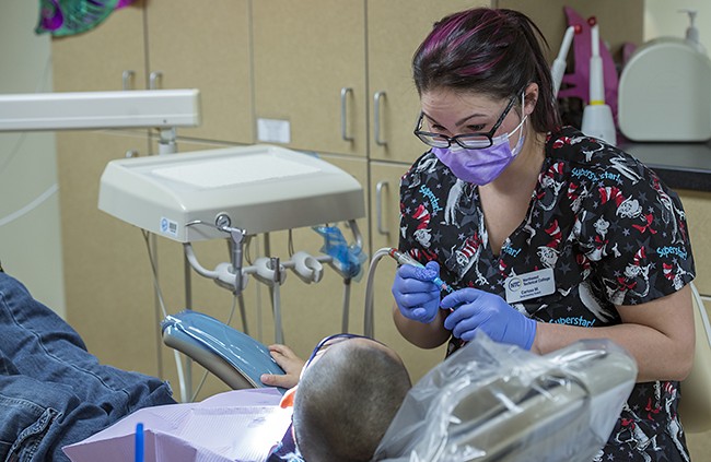 NTC student providing dental care during NTC's annual Give Kids a Smile free dental care event.