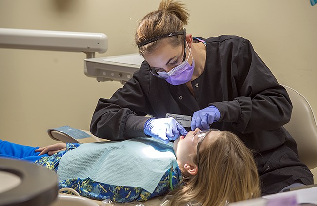 NTC student providing dental care during NTC's annual Give Kids a Smile free dental care event.