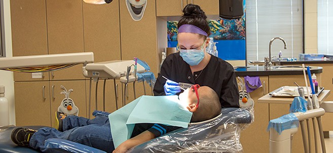 NTC student providing dental care during NTC's annual Give Kids a Smile free dental care event.