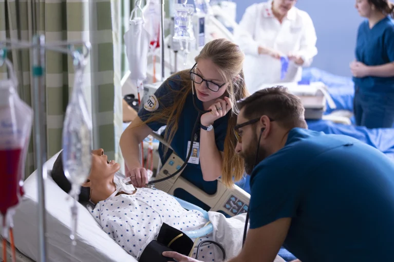 two nursing students working on a patient