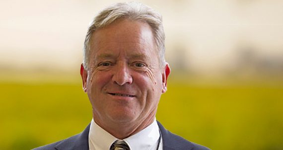 Portrait of executive financial director standing at office while looking at camera and smiling.