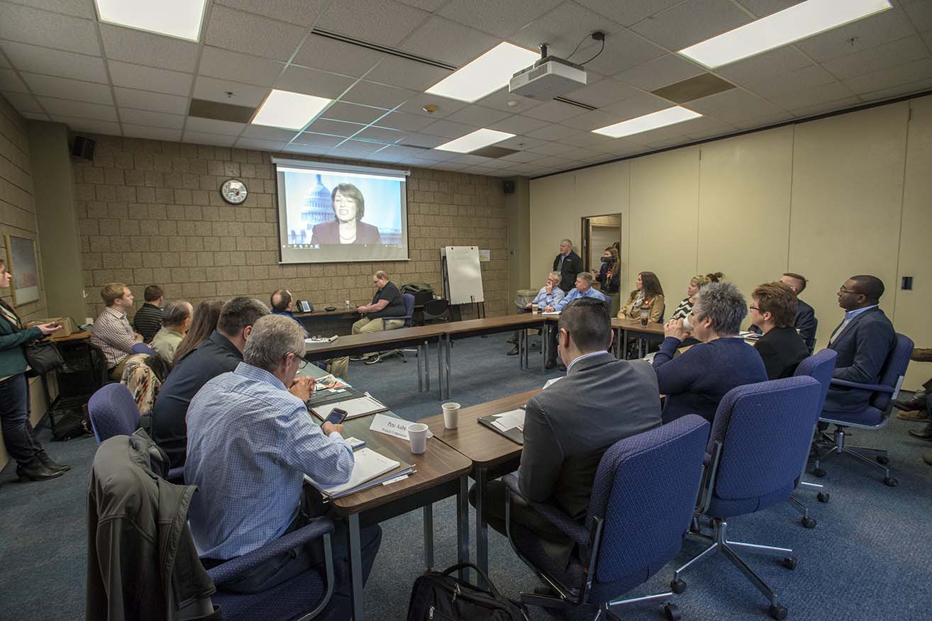 Panel participants at Northwest Technical College view a video message from U.S. Sen. Nancy Klobuchar.