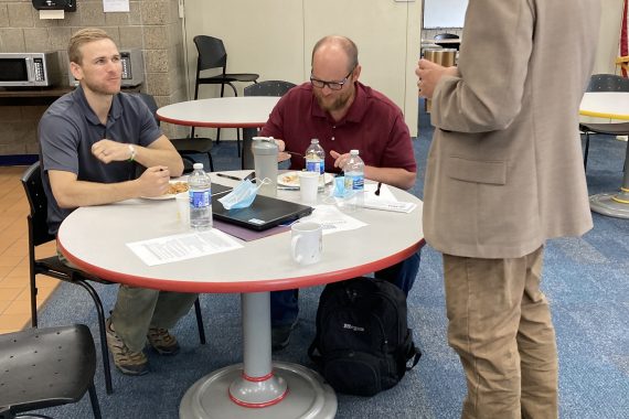 3 NTC employees talk around a table at Admin Day
