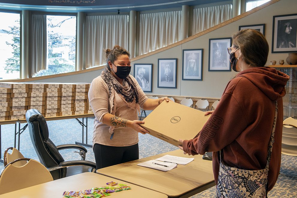 Ann Humphrey, associate director of retention at Northwest Tech's American Indian Resource Center, handing a laptop to a grant recipient