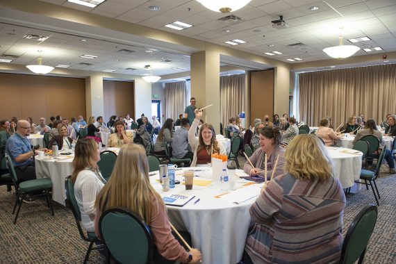 Attendees sitting at tables and smiling during NTC's Fifth Annual Community Health Worker Conference