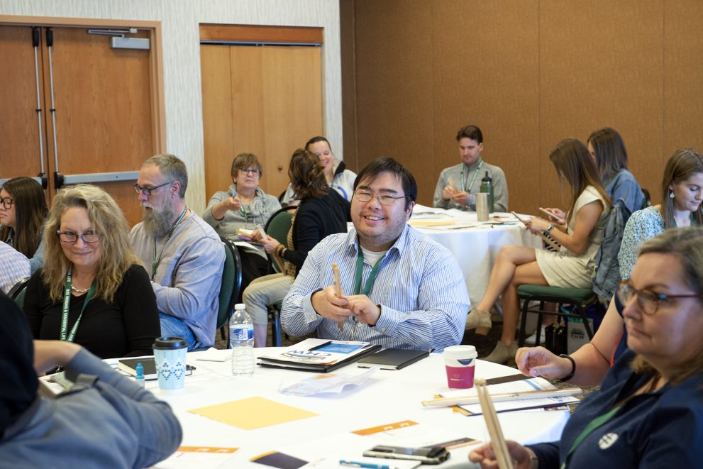 An attendee smiling during a presentation during NTC's Fifth Annual Community Health Worker Conference