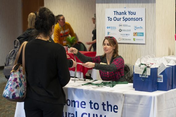 Angie Clark, summer program director, handing out welcome packets at the conference