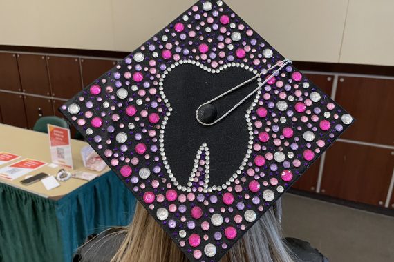 A bejeweled grad cap with a tooth in the center
