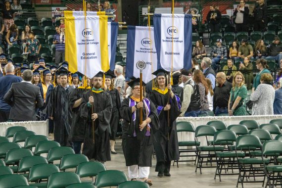 An NTC faculty member leads a processional of graduates into the Sanford Center