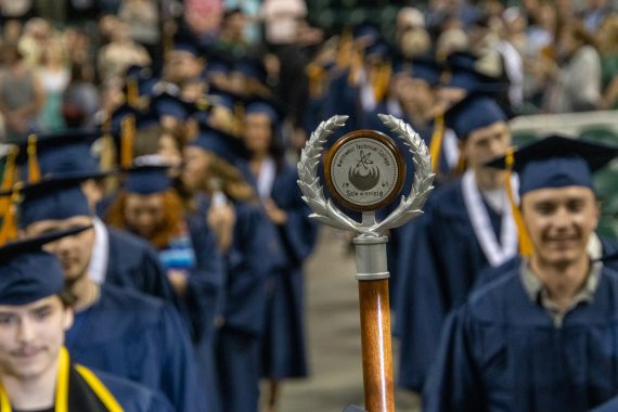 An ornately-decorated staff with a logo representing graduation