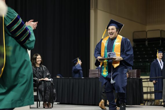 An NTC graduate excitedly walks across the state at the Sanford Center