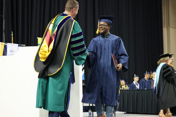 A graduate shakes President John Hoffman's hand