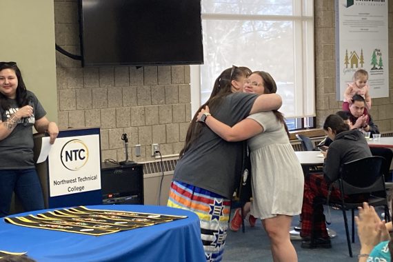 An NTC student hugs Chrissy Downwind, vice president for American Indian student success, after receiving her graduation stole