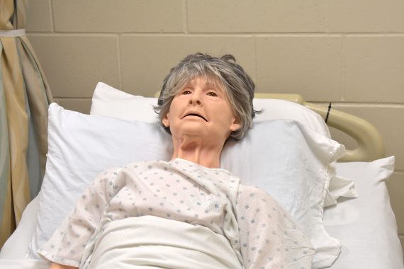 A mannequin of an elderly woman with short grey hair is tucked into a hospital bed in the Sanford/NTC Health Sciences Lab for CNA students at Bemidji High School