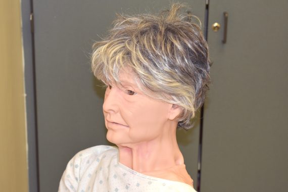A mannequin of an elderly woman with short gray hair