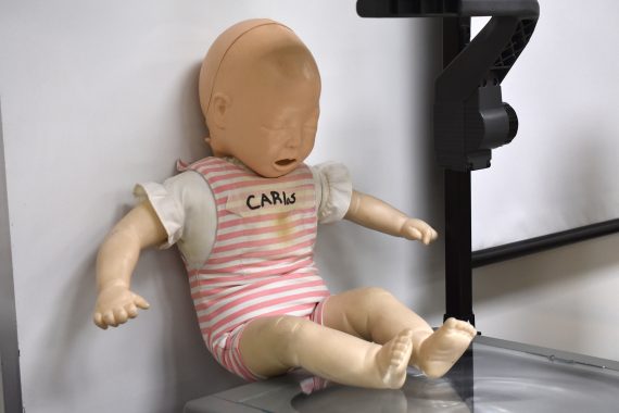 An infant mannequin with the name "Carlos" written across its chest