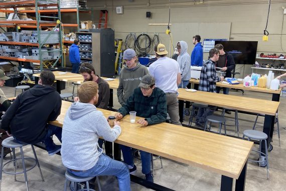 Many NTC students are socializing around two long tables