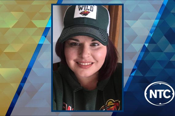 A portrait of a woman with long brown hair wearing a Minnesota Wild jacket and cap.