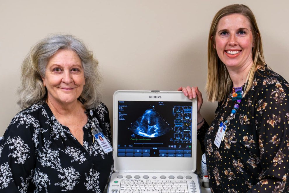 Maggie Wolverton and Mindy Williams stand next to a Philips sonography machine.