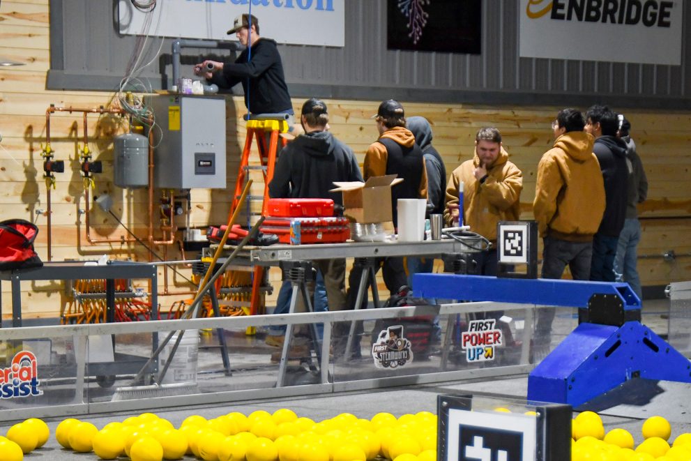 NTC students install a ventilation pipe onto a boiler at the North STAR Robotics building in Bemidji.